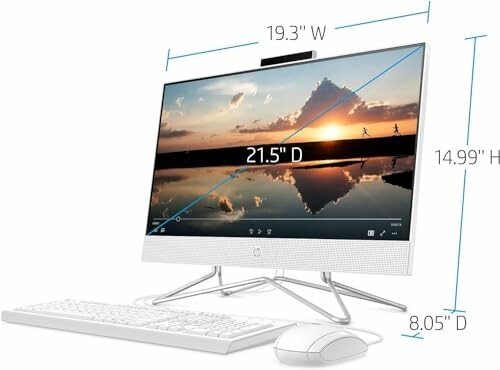 All-in-one desktop computer with keyboard and mouse, screen displaying a sunset scene, dimensions labeled.