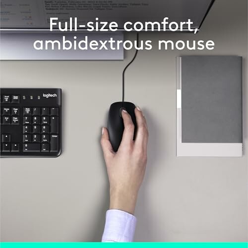Hand using ambidextrous mouse with keyboard and notebook nearby.