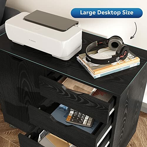 Printer and headphones on a black desk with open drawers showing books and a calculator.
